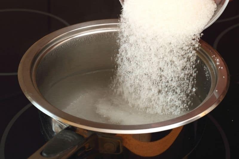 Zucker in Kochtopf mit Wasser geben