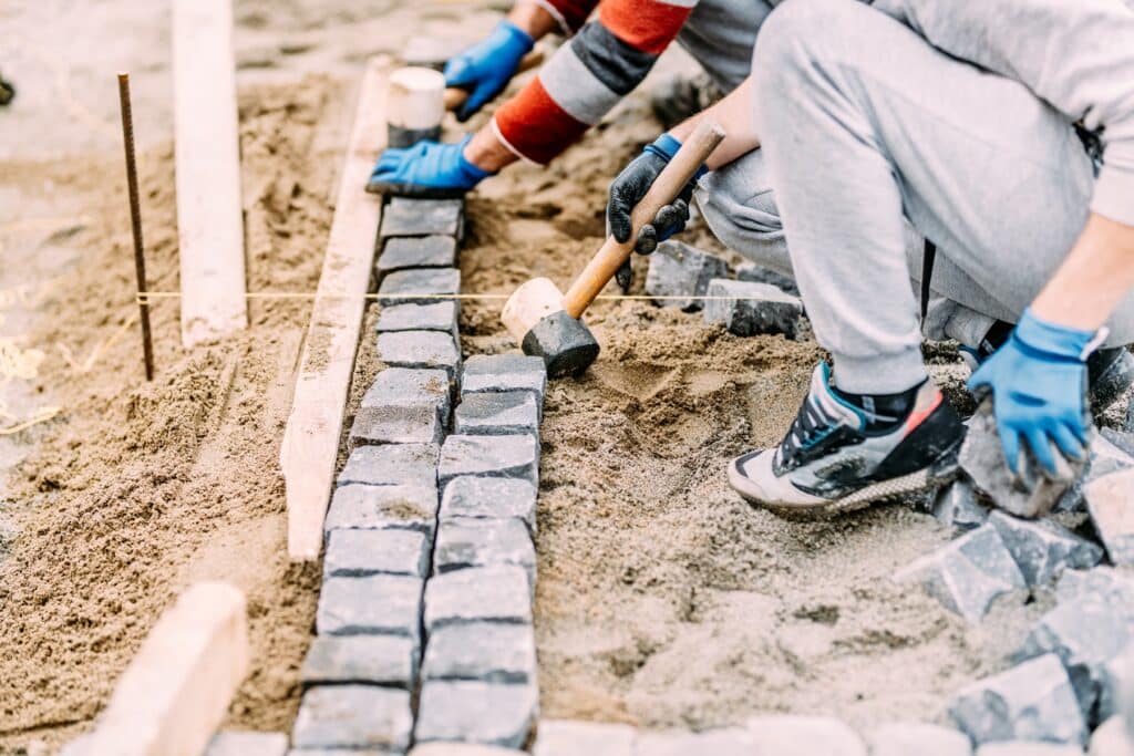 Arbeiter verlegen Pflastersteine auf Sand